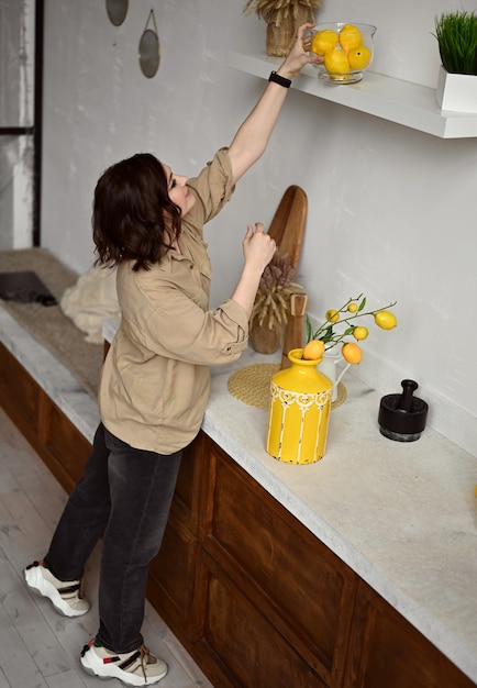 Foto linda garota em uma cozinha bege com limões amarelos estilo siciliano itália