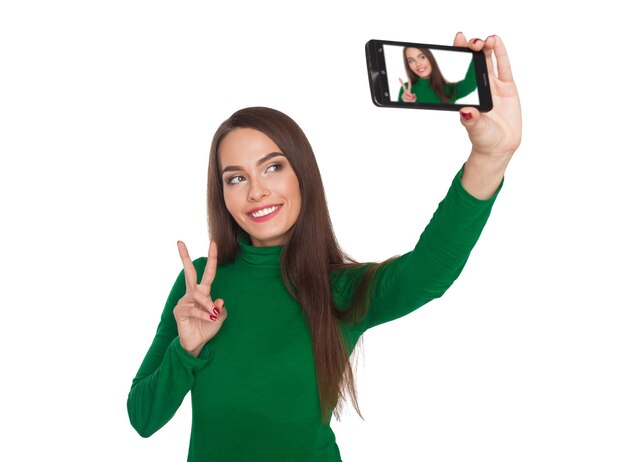Linda garota em uma gola verde fotografando selfie