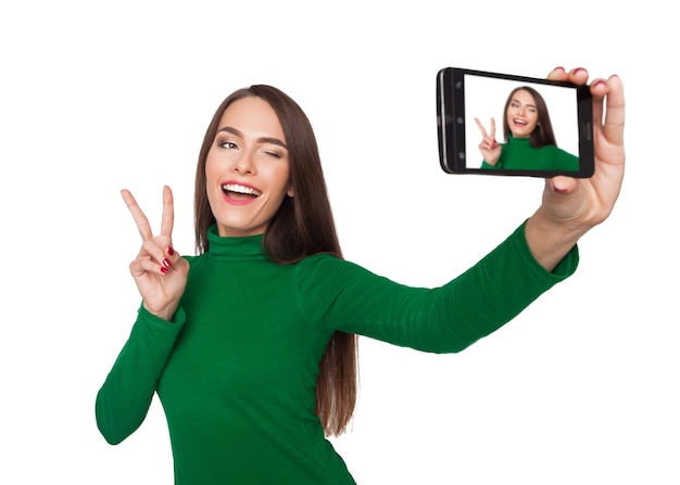 Linda garota em uma gola verde fotografando selfie