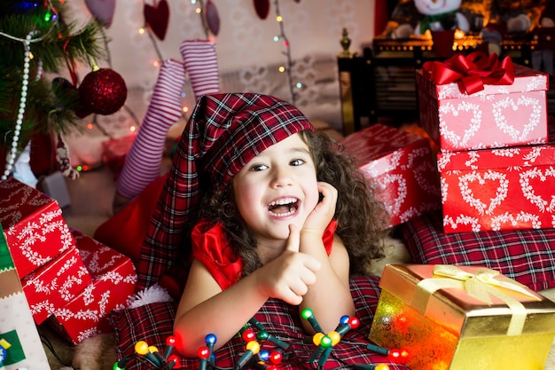 linda garota encaracolada se divertindo perto da árvore de natal