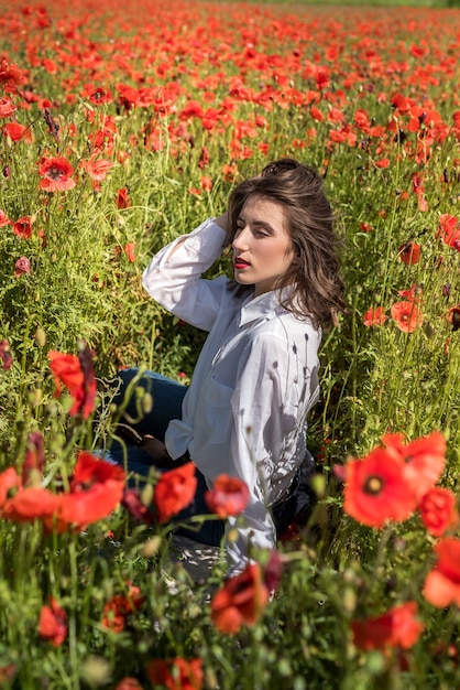 Linda garota encontra-se em um campo de papoulas vermelhas. estilo de vida saudável. horário de verão