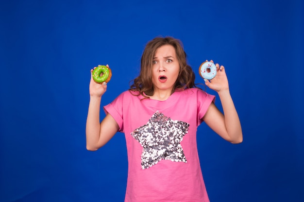 Linda garota engraçada com donuts no azul.