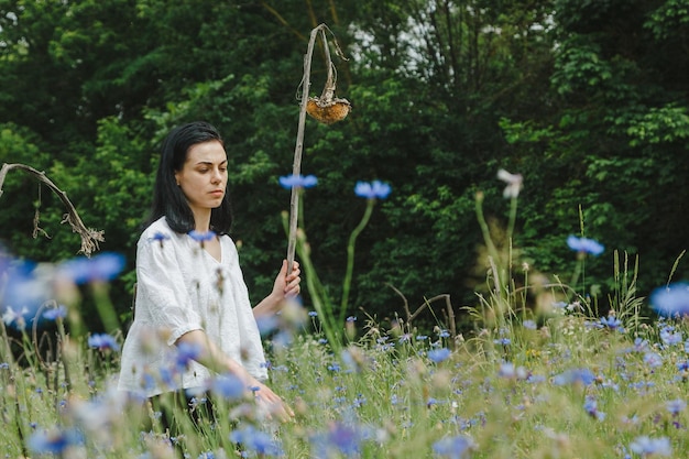 Linda garota entre o campo de verão com flores silvestres