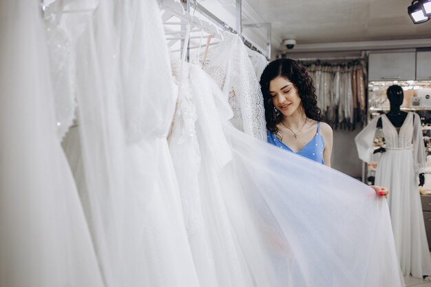 Linda garota escolhe um vestido de noiva no salão de casamento