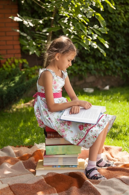 Linda garota esperta lendo um grande livro no parque em um dia de sol