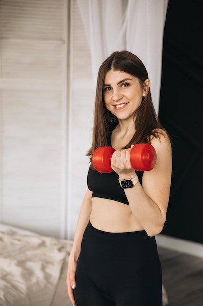 Linda garota esportiva fazendo exercícios com halteres em casa foto de alta qualidade