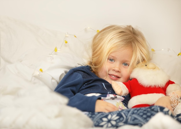 Linda garota está animada deitada no fundo branco e segurando o papai noel, feriado de natal