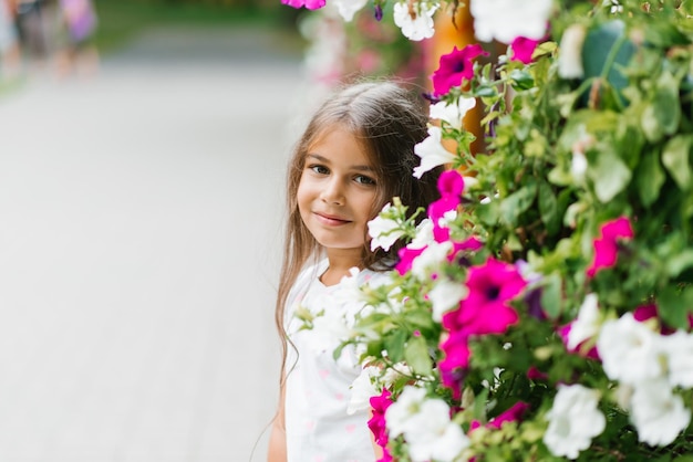 Linda garota está descansando no parque no verão entre as flores nas férias de verão