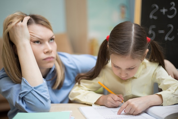 Linda garota está estudando em casa com a mãe