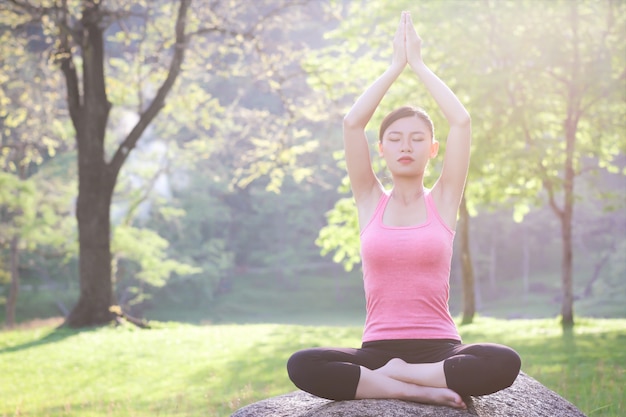 Linda garota está jogando yoga no parque. No meio da natureza Conceito de exercício