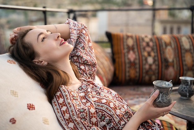 Linda garota está relaxando com uma xícara de chá no sofá