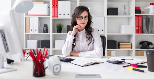 Linda garota está sentado à mesa no escritório.