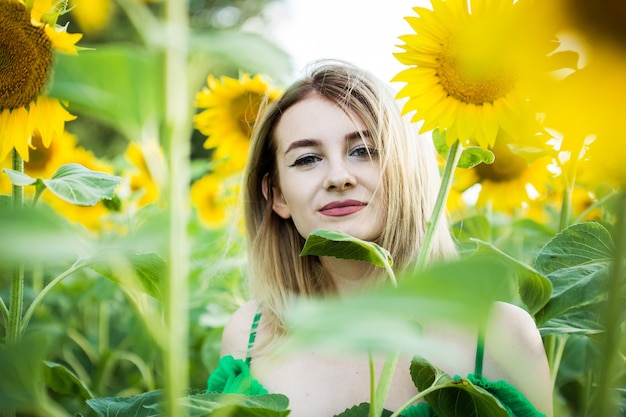 Linda garota europeia com um vestido verde na natureza com girassóis