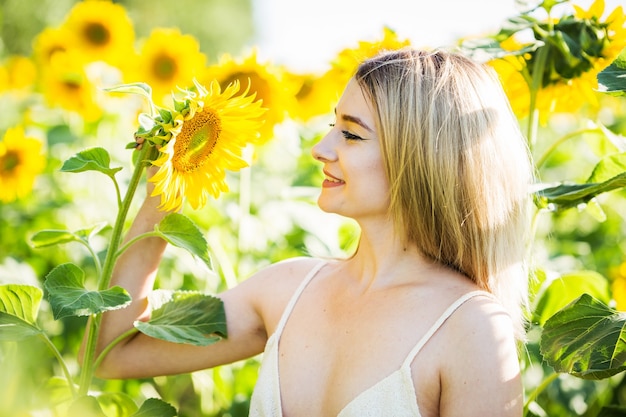 Linda garota europeia em um vestido branco na natureza com girassóis