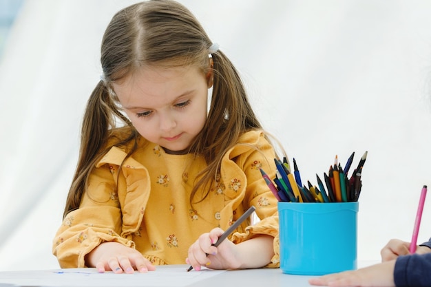 Linda garota europeia pintando com lápis colorido conceito de educação infantil do jardim de infância