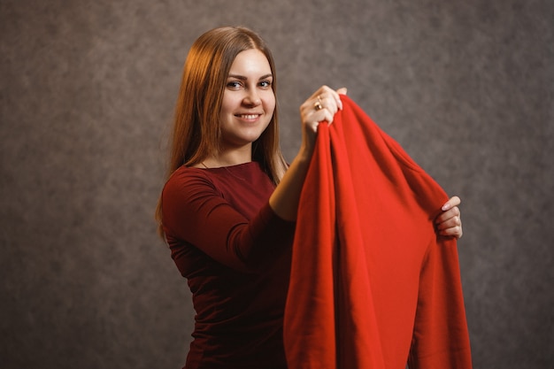 Linda garota experimentando um suéter vermelho