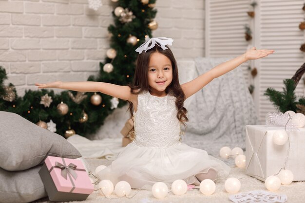 Linda garota fazendo flocos de neve de papel para decorar o Natal