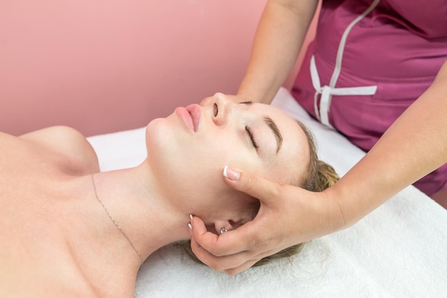 Linda garota fazendo massagem facial na clínica de beleza