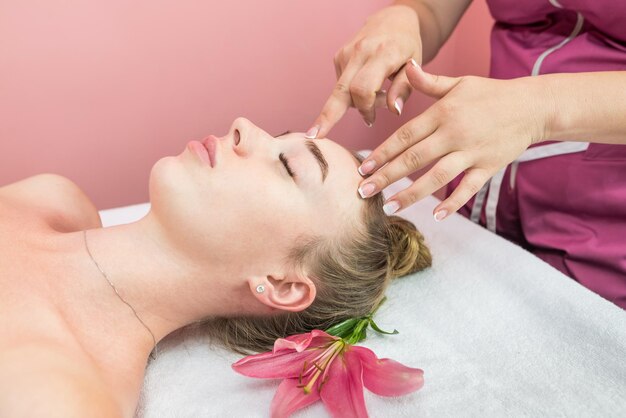 Linda garota fazendo massagem facial na clínica de beleza