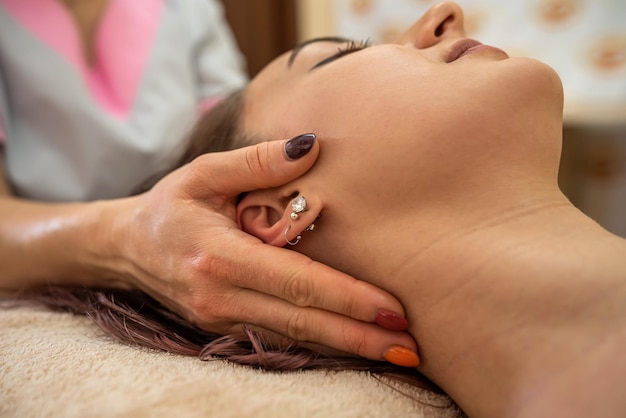 Linda garota fazendo uma massagem facial rejuvenescedora na sala de aroma