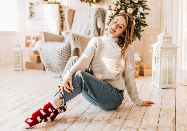 Linda garota feliz com presentes de Natal perto da árvore de ano novo