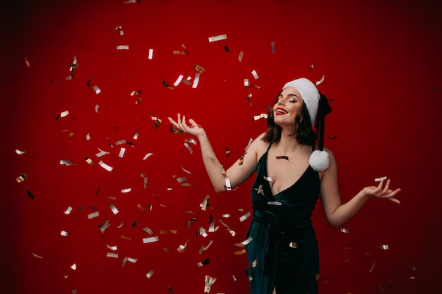 Linda garota feliz com um chapéu de Papai Noel jogando confete no conceito de ano novo