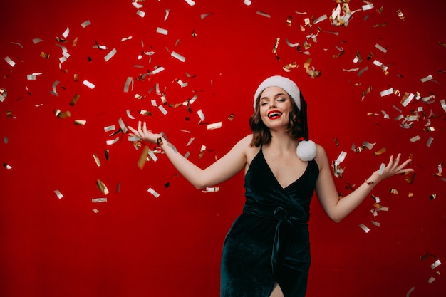 Linda garota feliz com um chapéu de Papai Noel jogando confete no conceito de ano novo