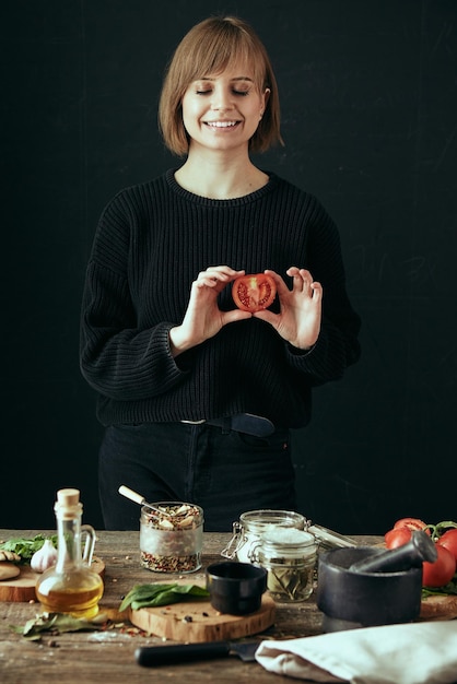 Linda garota feliz cozinha comida saudável na cozinha tomate na mão conteúdo de blog de comida de estilo de vida saudável