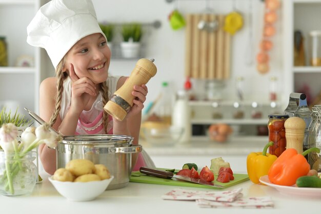 Foto linda garota feliz cozinhando na cozinha