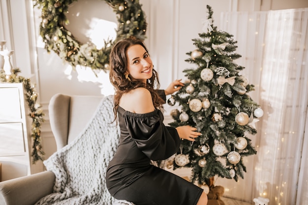 Linda garota feliz decorando brinquedos de Natal para árvore de ano novo