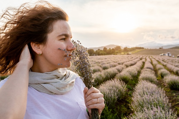 Linda garota fica antes do pôr do sol e sonhadora cheira lavanda