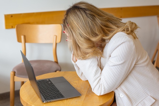 Linda garota freelancer se sentindo cansada e estressada enquanto usa um laptop e trabalha remotamente.