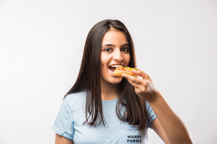 Foto linda garota indiana asiática comendo uma fatia de pizza em pé, isolada sobre um fundo branco