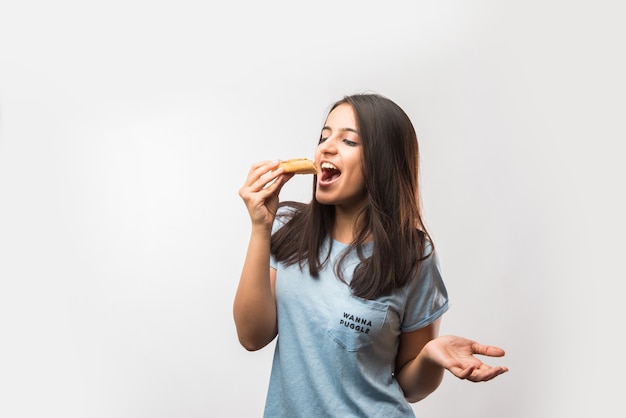 Foto linda garota indiana asiática comendo uma fatia de pizza em pé, isolada sobre um fundo branco