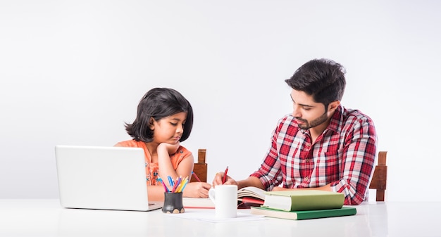 Linda garota indiana com o pai estudando ou fazendo lição de casa em casa usando laptop e livros - conceito de escolaridade online