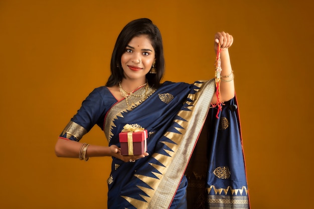 Linda garota indiana mostrando Rakhis e a caixa de presente por ocasião do Raksha Bandhan. A irmã associa Rakhi como um símbolo de amor intenso por seu irmão.