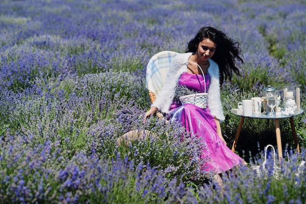 Linda garota indiana usa vestido tradicional saree índia sentado no campo de lavanda roxo com decoração.