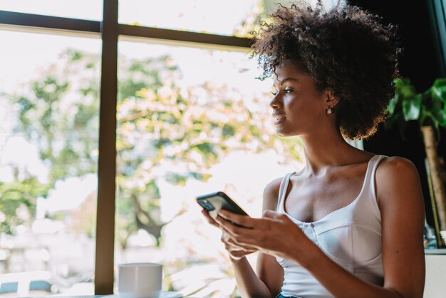 Linda garota latina usando seu celular no café