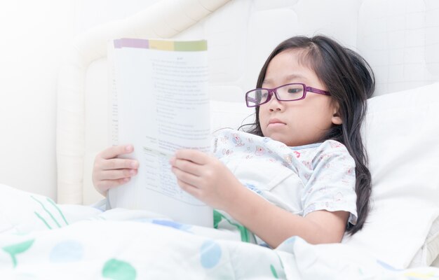 Linda garota lendo livro na cama