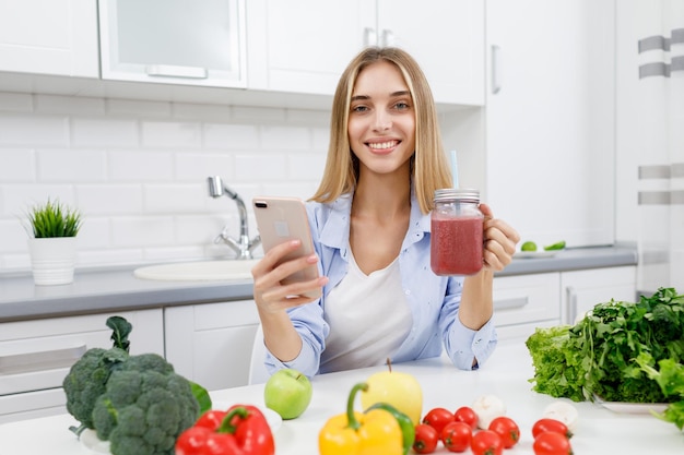 Linda garota loira bebendo smoothie e fazendo uma selfie