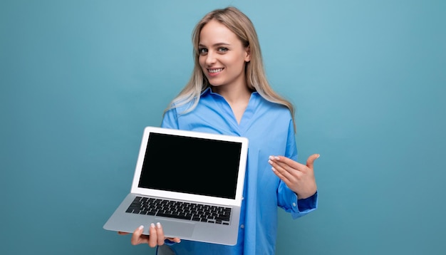 Linda garota loira com um laptop nas mãos com um mocup sobre um fundo azul