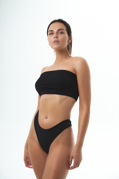 Linda garota magra, fitness, figura de pele bronzeada em lingerie esportiva de tópico preto