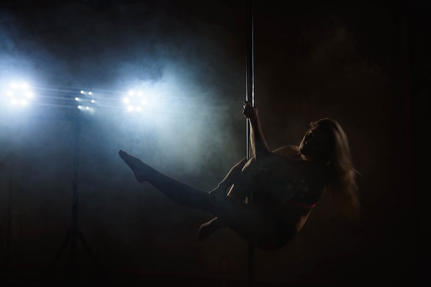 Linda garota magro com pilão. Mulher de dançarina de pole feminino dançando em um poste