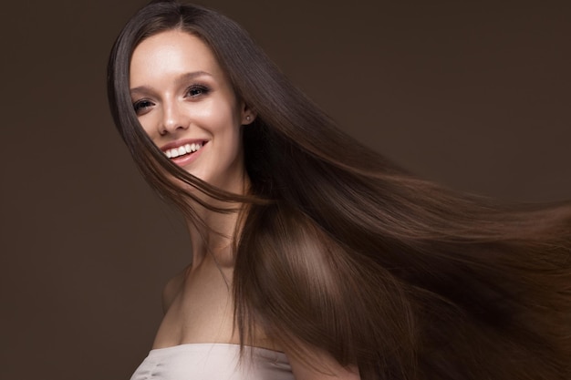 Foto linda garota morena em movimento com um cabelo perfeitamente liso e maquiagem clássica rosto de beleza foto tirada no estúdio