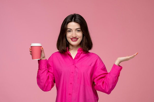 Linda garota muito adorável na camisa rosa com batom vermelho segurando a xícara de café rosa