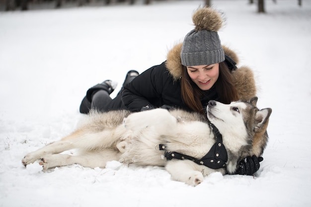 Linda garota na floresta de inverno com cachorro Brinque com o cachorro Husky Siberiano