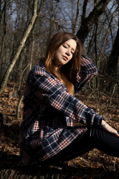 Linda garota na floresta perto das árvores