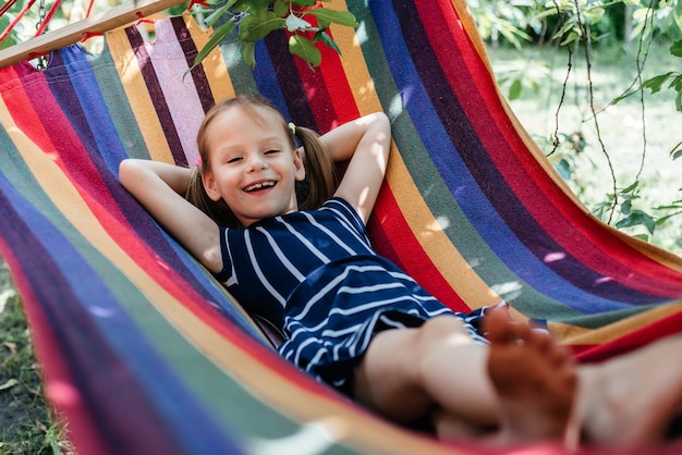 Linda garota na rede colorida de fundo de verão, atividades de outdor de férias de verão