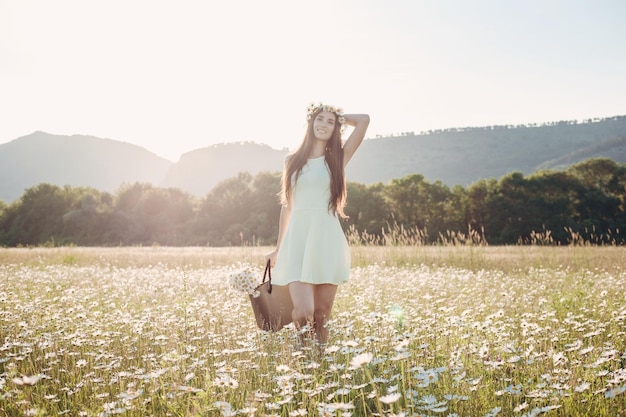 Linda garota no campo de margaridas Por do sol de verão jovem feliz e conceito de harmonia de natureza springgreen Mulher morena feliz despreocupada com cabelos ondulados saudáveis se divertindo ao ar livre na natureza