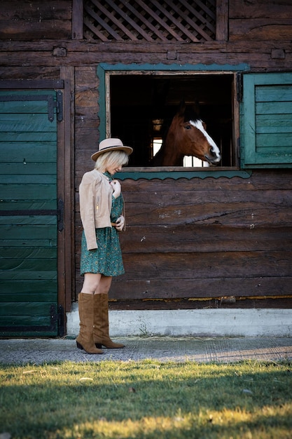 Linda garota no estilo boho fala com um cavalo através de uma janela